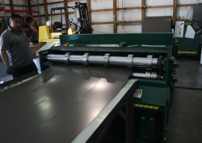 Person standing next to industrial sheet metal working machinery in a workshop.